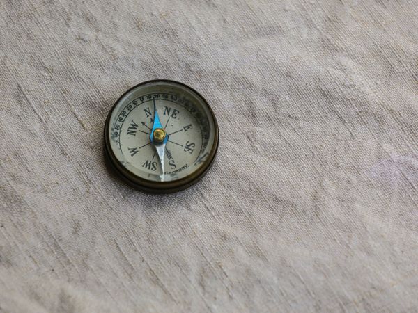 Compass pointing north sitting on a piece of white fabric.