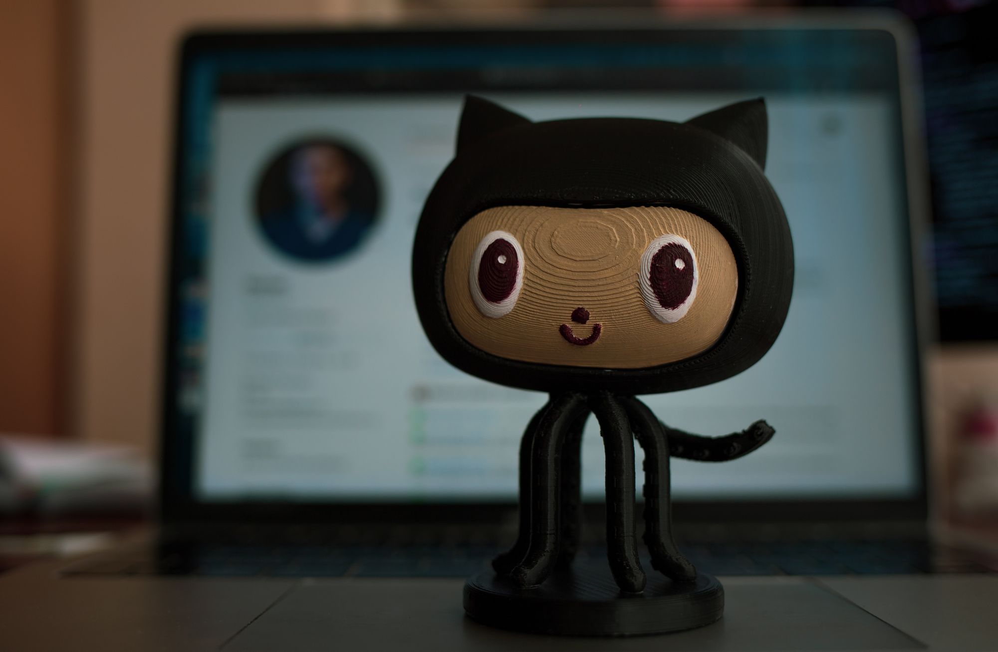 GitHub's mascot sitting on top of a MacBook's trackpad.