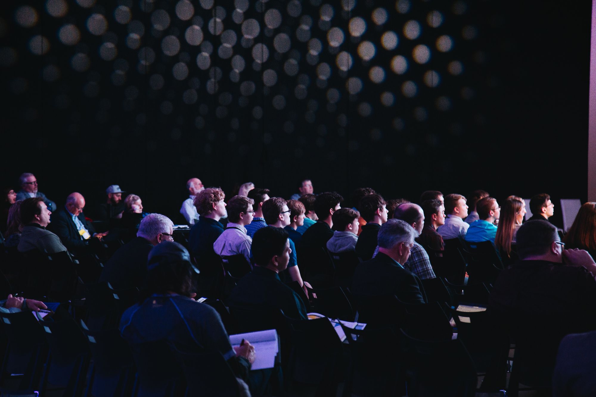 Large group of seated people in a dark room.