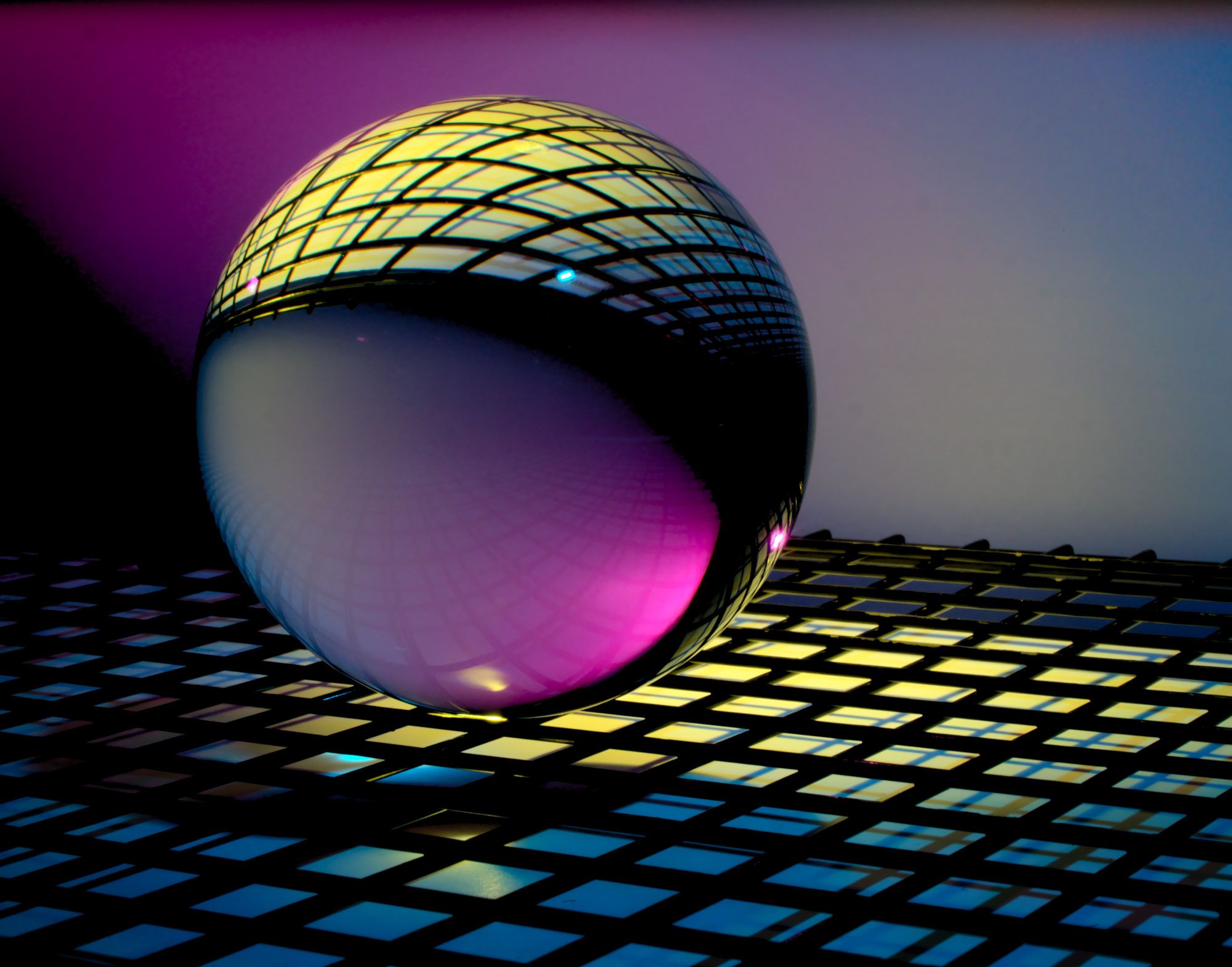 Colorful sphere sitting on a lit up grid.
