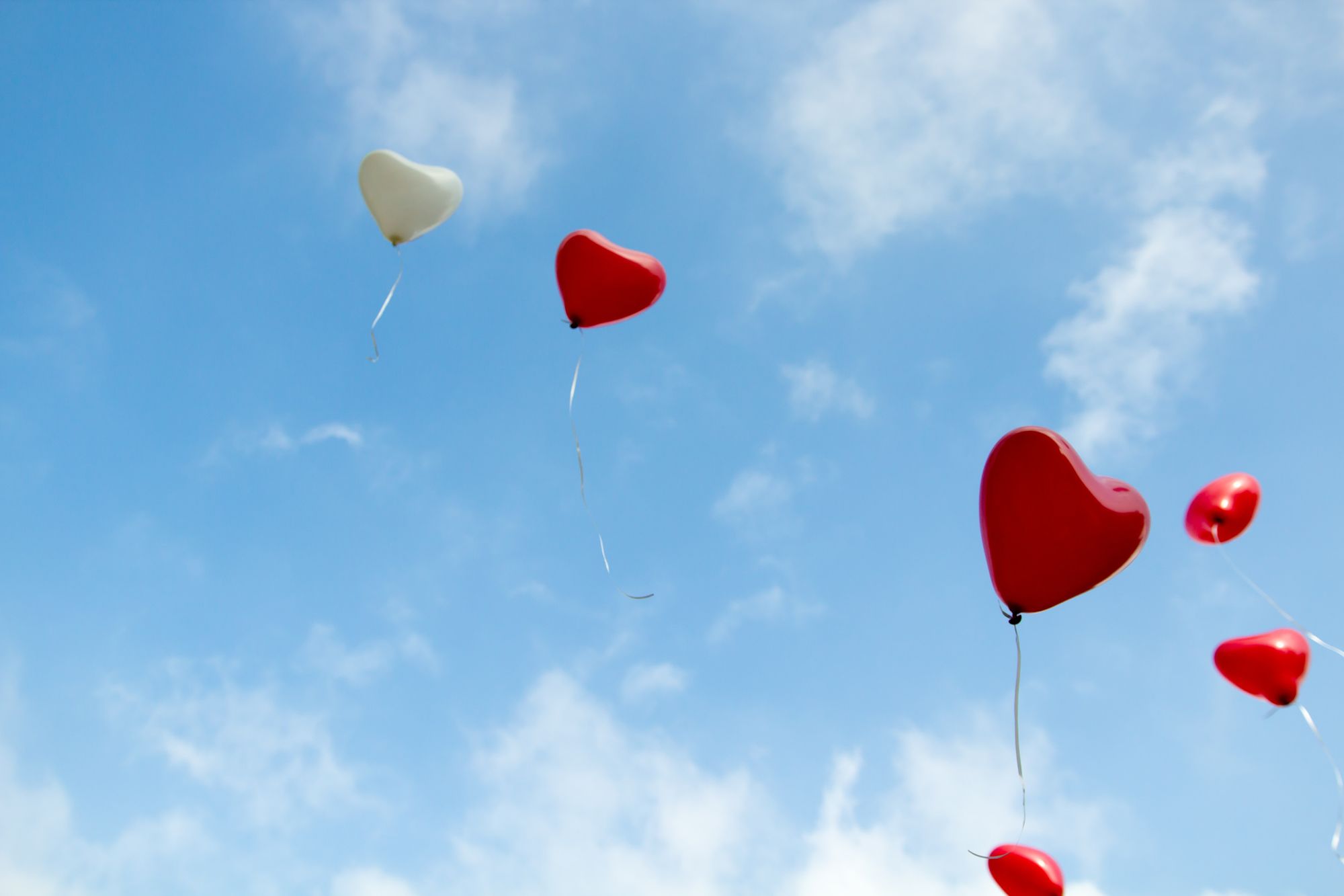 Heart-shaped balloons flying in the clouds.