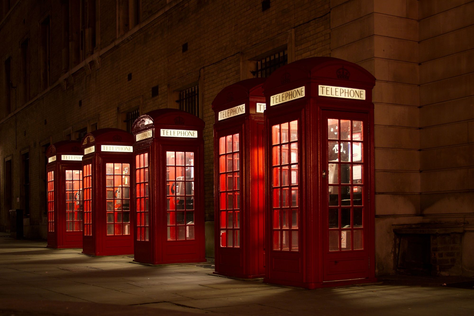 Five telephone booths next to each other at night.