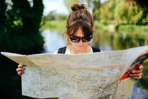 Woman, with her back to a river, studying a paper map.