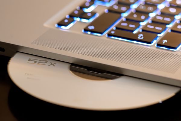 MacBook with a CD sticking out from its CD drive on the side.