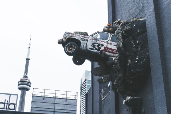 Car crashing through the side of a tall building.