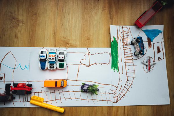 Drawing of streets on paper with toy cars on top.