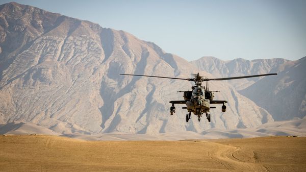 Apache helicopter flying through a desert.