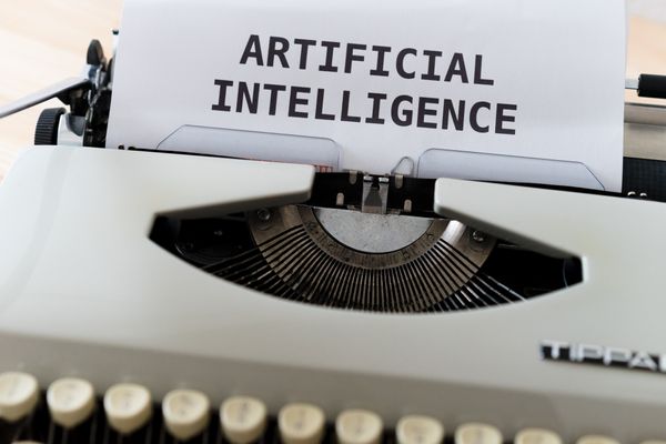 Typewriter with a piece of paper on which it says "Artificial Intelligence".